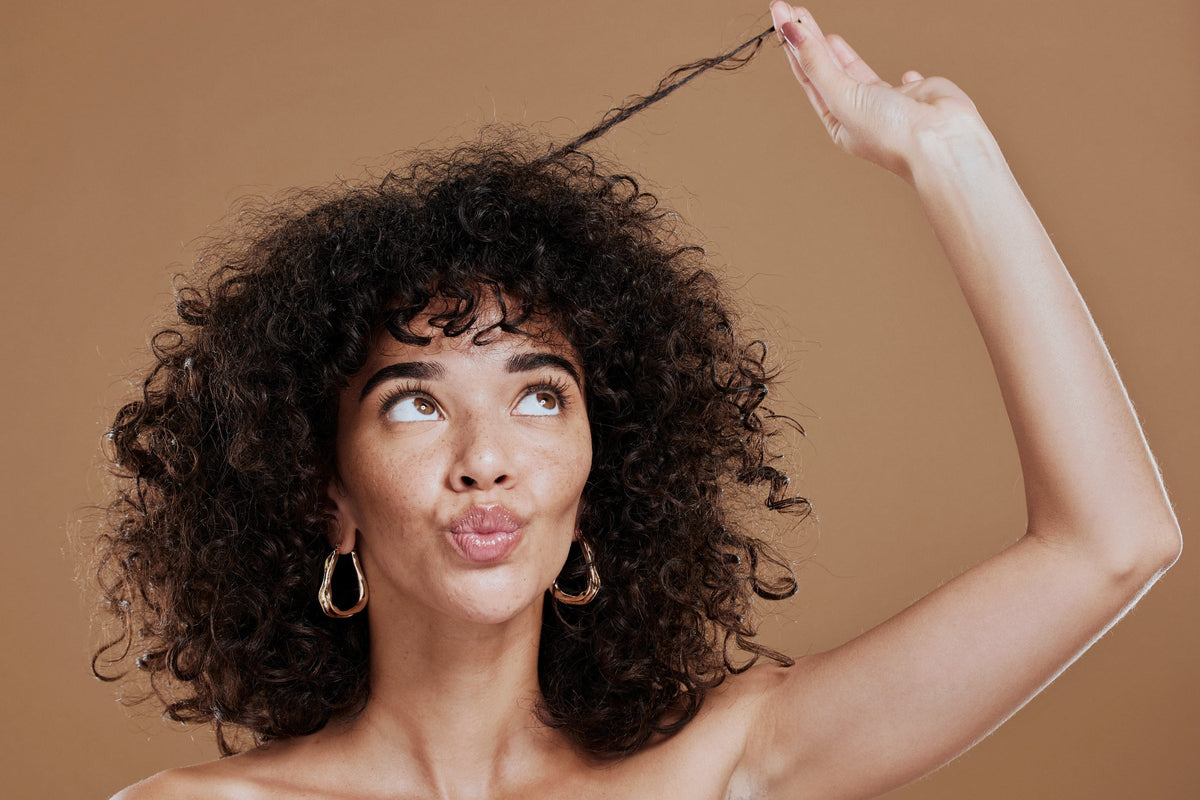 A woman holding up her curly hair to show its texture