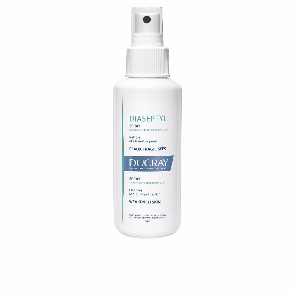 Ducray White plastic spray bottle with blue and green text, spray nozzle and ribbed grip, minimalist clinical design