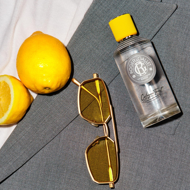 Roger &amp; Gallet Transparent glass cologne bottle with clear yellow liquid, ribbed yellow cap, round gray label, black cursive text, presented .