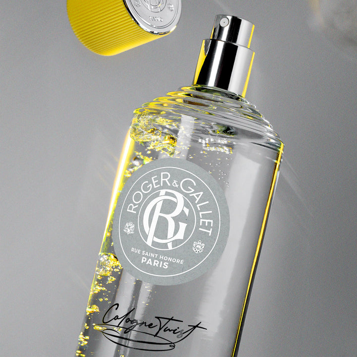 Roger &amp; Gallet Transparent glass cologne bottle with clear yellow liquid, ribbed yellow cap, round gray label, black cursive text, presented .